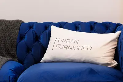 a blue couch with a pillow with the words urban furnished at 240-11 NEW STUDIO Prime Upper East W&D in New York