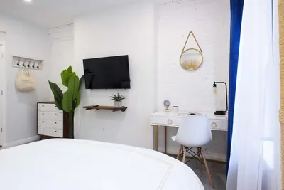 a bedroom with a bed and a desk and a tv at 240-12 BRAND NEW Studio Prime location W&D in New York