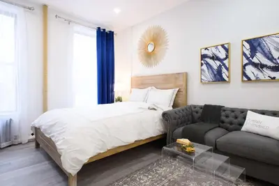 a bedroom with a bed and a couch at 240-12 BRAND NEW Studio Prime location W&D in New York