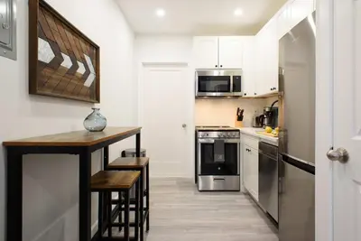 a kitchen with white cabinets and a wooden counter top at 240-12 BRAND NEW Studio Prime location W&D in New York