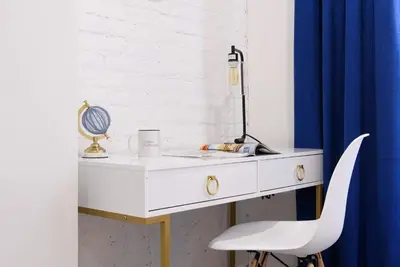 a white desk with a lamp and a white chair at 240-12 BRAND NEW Studio Prime location W&D in New York
