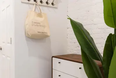 a tan bag hanging on a wall next to a cabinet at 240-12 BRAND NEW Studio Prime location W&D in New York