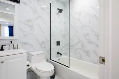 a white bathroom with a shower and a toilet at 240-12 BRAND NEW Studio Prime location W&D in New York