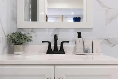 a bathroom sink with a black faucet and a mirror at 240-15 Luxury Studio Prime Location W&D in New York