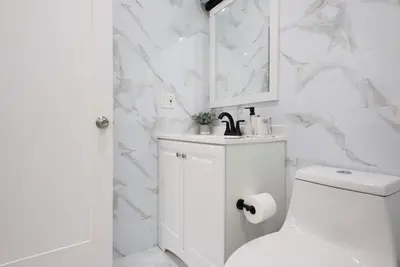a white bathroom with a toilet and a mirror at 240-15 Luxury Studio Prime Location W&D in New York