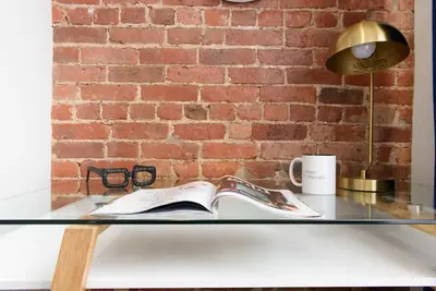 a glass table with a book and a lamp and a brick wall at 240-15 Luxury Studio Prime Location W&D in New York