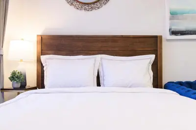 a white bed with white pillows and a wooden headboard at 240-5 NEW Prime Location STUDIO W&D in unit in New York