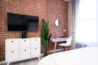 a bedroom with a tv on a brick wall at 240-5 NEW Prime Location STUDIO W&D in unit in New York