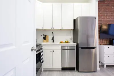 a kitchen with white cabinets and a stainless steel refrigerator at 240-5 NEW Prime Location STUDIO W&D in unit in New York