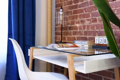 a glass table and white chairs next to a brick wall at 240-6 NEW STUDIO Prime Location W&D in unit in New York