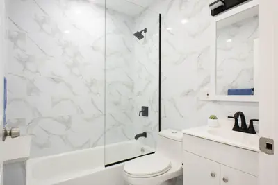 a white bathroom with a shower and a toilet at 240-6 NEW STUDIO Prime Location W&D in unit in New York