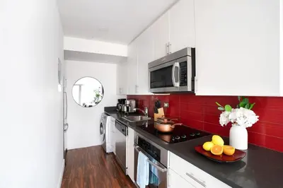 a kitchen with white cabinets and red tiles at 809-6A NEW 2BR Private Roof & City View in New York