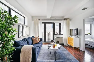 a living room with a blue couch and a tv at 809-6A NEW 2BR Private Roof & City View in New York