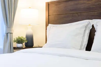 a bed with white pillows and a lamp on a table at 240-9 Luxury Prime Location STUDIO W&D in New York