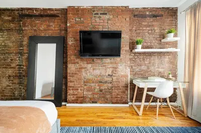 a bedroom with a brick wall with a tv and a table at 26-3A STUDIO Gramercy W D Outdoor Courtyard in New York
