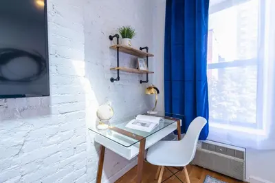 a desk and a chair in a room with a window at 26-4A New Studio prime 20's W D Shared Courtyard in New York