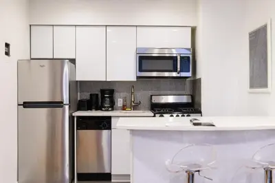 a kitchen with white cabinets and a stainless steel refrigerator at 26-4B Newly Furnished 1BR W D Courtyard in New York