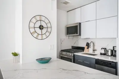 a kitchen with white cabinets and a clock on the wall at 1597-10 New Studio Upper East Side W&D in unit in New York