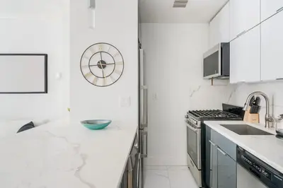 a kitchen with white marble countertops and a clock on the wall at 1597-10 New Studio Upper East Side W&D in unit in New York