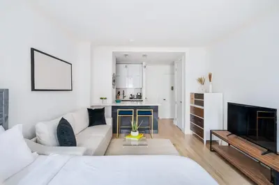 a white living room with a couch and a kitchen at 1597-10 New Studio Upper East Side W&D in unit in New York