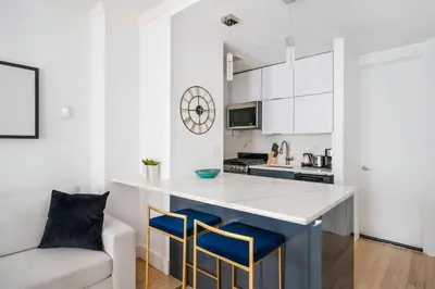 a kitchen with white cabinets and blue stools at 1597-10 New Studio Upper East Side W&D in unit in New York
