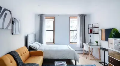 a bedroom with a bed and a couch and a desk at 1597-11 Studio - Upper East Side Apt W&D in New York