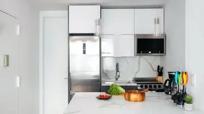 a kitchen with white cabinets and a stainless steel refrigerator at 1597-11 Studio - Upper East Side Apt W&D in New York