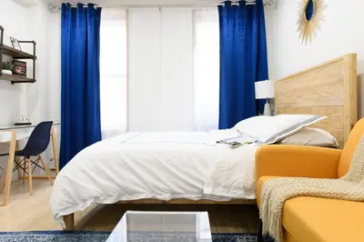 a bedroom with a bed with blue curtains and a couch at 1597-12 NEW Studio Prime UES WD in unit in New York