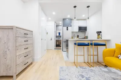 a living room with a yellow couch and a kitchen at 1597-13 I Brand new Studio Prime upper east W&D in New York
