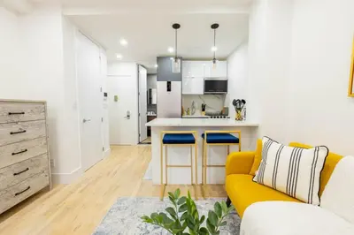 a living room with a yellow couch and a kitchen at 1597-13 I Brand new Studio Prime upper east W&D in New York