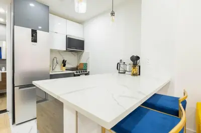 a white kitchen with a large white counter top at 1597-1 Large studio W D in the unit prime UES in New York