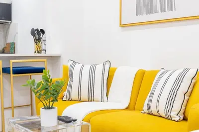 a yellow couch with striped pillows and a table at 1597-1 Large studio W D in the unit prime UES in New York