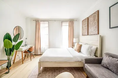 a white bedroom with a bed and a couch at 1597-2 Luxury Upper East Side Studio W&D in New York