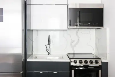 a white kitchen with a sink and a microwave at 1597-3 Studio Upper East Side Apt W&D in unit in New York