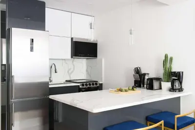 a kitchen with white cabinets and a counter with blue stools at 1597-3 Studio Upper East Side Apt W&D in unit in New York
