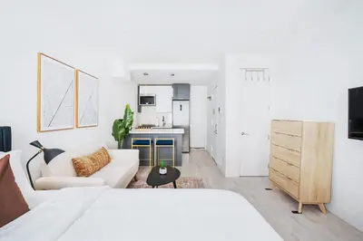 a white living room with a white couch and a kitchen at 1597-4 Brand new Prime UES W D walk to C park in New York