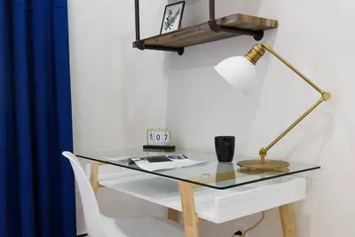 a glass desk with a lamp and a blue curtain at 1597-5 New Studio Prime UES W D in unit in New York