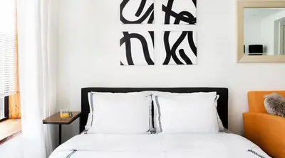 a bedroom with a bed with white sheets and an orange chair at 1597-6 Luxury Studio Upper East Side W&D in New York