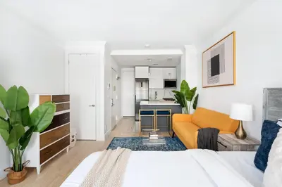 a living room with a yellow couch and a kitchen at 1597-7 Luxury Upper East Studio W&D in unit in New York