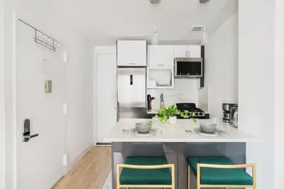 a kitchen with white cabinets and green chairs at 1597-PHN PH Duplex -Private Outdoor Deck W D in New York