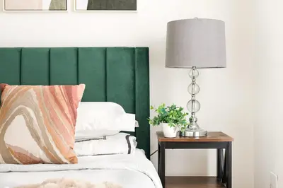a bedroom with a green headboard and a table with a lamp at 1597-PHN PH Duplex -Private Outdoor Deck W D in New York