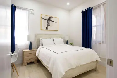 a bedroom with a large bed with blue curtains at 78-1A NEW Modern 1BR W&D Walk to Central Park in New York