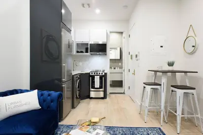 a living room with a blue couch and a kitchen at 78-1B New 1BR prime UES WD in unit BEST VALUE in New York