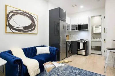 a living room with a blue couch and a kitchen at 78-1B New 1BR prime UES WD in unit BEST VALUE in New York