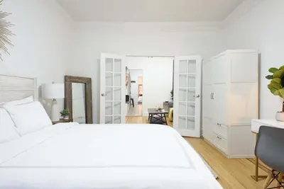 a white bedroom with a large white bed and a chair at 1567-1A New 2br PRIME upper East APT W&D in New York