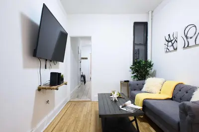 a living room with a couch and a tv on a wall at 1567-1A New 2br PRIME upper East APT W&D in New York