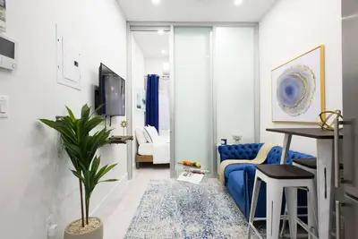 a living room with a blue couch and a tv at 78-1D NEW Junior 1 BR Prime UES WD in unit in New York