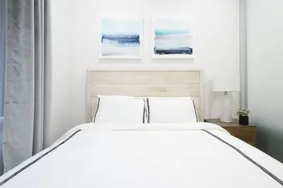 a white bed in a bedroom with two paintings on the wall at 78-2D New furnished 1BR WD walk to Central Park in New York