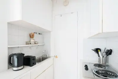 a white kitchen with a sink and a microwave at 11-4F Prime west village designer 1BR in New York