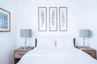 a bedroom with a white bed with three pictures on the wall at 102-1A Best Value 2BR Apt Near Central Park in New York
